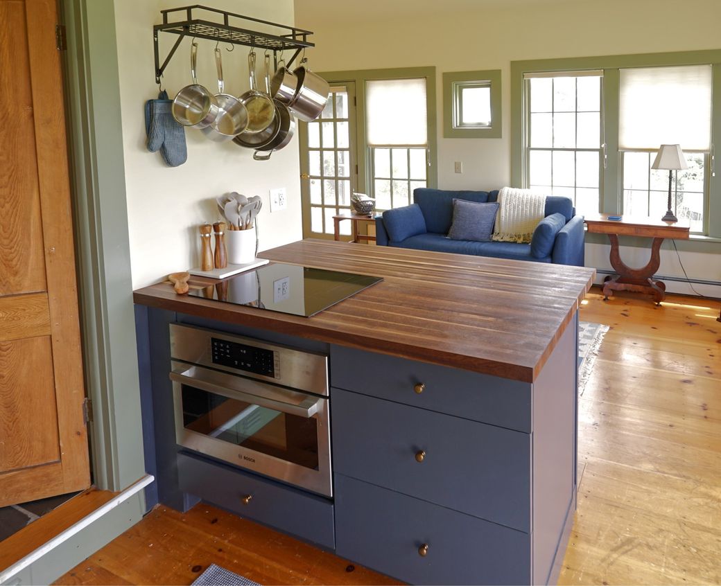 The kitchen at Whitford House, with the induction cooktop set into the butcher-block island and the sitting room beyond.