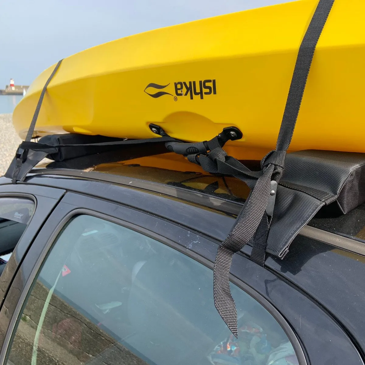 Close-up of a cam strap running over a kayak and down through the car's door opening